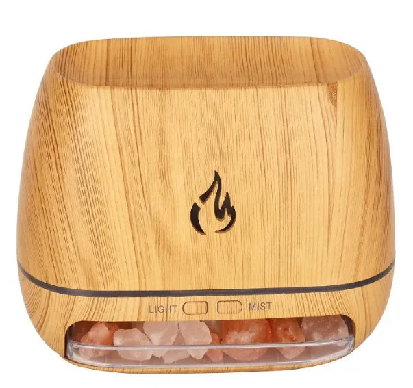 Two flame diffusers, one with a gray stone-like base and another with a brown wooden base, both emitting a yellow mist to simulate a flame effect, placed on flat surfaces.