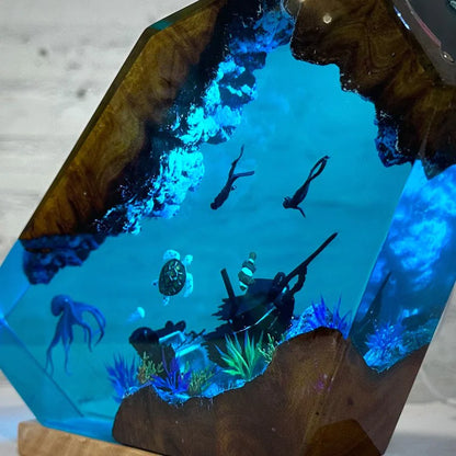 Wooden sculpture with blue resin and underwater scene, including fish and a turtle.
